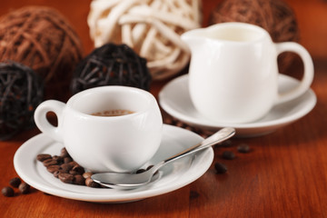 White espresso coffee Cup, coffee beans and milk jug on wooden background. Concept of coffee breaks and serving coffee