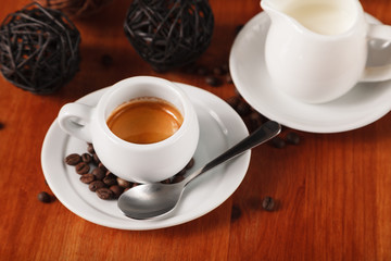 White espresso coffee Cup, coffee beans and milk jug on wooden background. Concept of coffee breaks and serving coffee