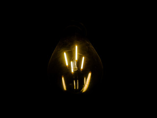 lightbulb on dark background with bright yellow shining wire