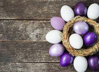 Bright purple colored Easter eggs in nest on wooden background, selective focus image. Happy Easter...
