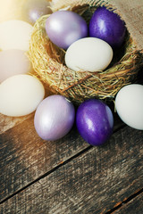Fototapeta na wymiar Bright purple colored Easter eggs in nest on wooden background, selective focus image. Happy Easter card