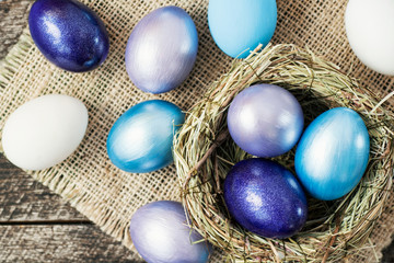 Fototapeta na wymiar Bright purple colored Easter eggs in nest on wooden background, selective focus image. Happy Easter card