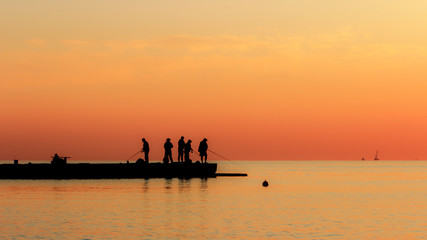 Naklejka na ściany i meble Fishermen catch fish at sunrise