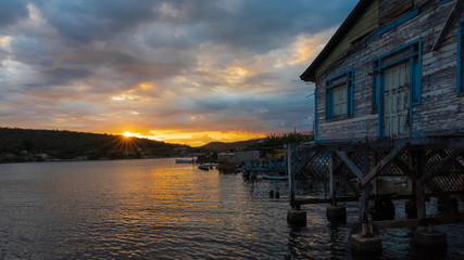 Fototapeta premium sunset at harbor of santiago de cuba with boathouse