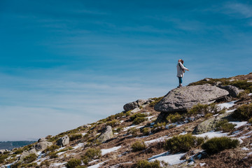 Young backpacker enjoying a sunny winter day in the mountains. Breathing fresh air, relaxed and carefree. Some snow all around. Amazing view. Lifestyle.