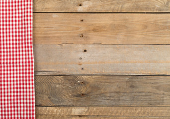 Red checkered dishcloth on brown rustic wooden plank table flat lay top view from above