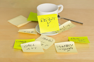 Coffee cup covered with sticky notes with different appointments on brown wooden desk in office