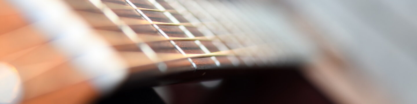 Griffbrett und Hals eines Hübschen Holz Gitarren Musikinstruments für Rockmusik in Oktav Resonanz vor unscharfem Hintergrund