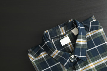 Folded checkered shirt on black table, space for text