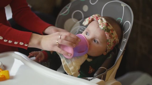 the little girl is drinking from the trough