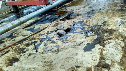 Spilled oil on sandy soil near pipelines and process equipment. Oil leaks during operation and...