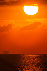 波を照らす朝の太陽と渡る船