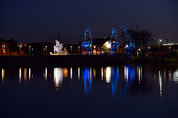 Colorfully illuminated antique cranes on the quay of Szczecin Łasztownia.  - obrazy, fototapety, plakaty