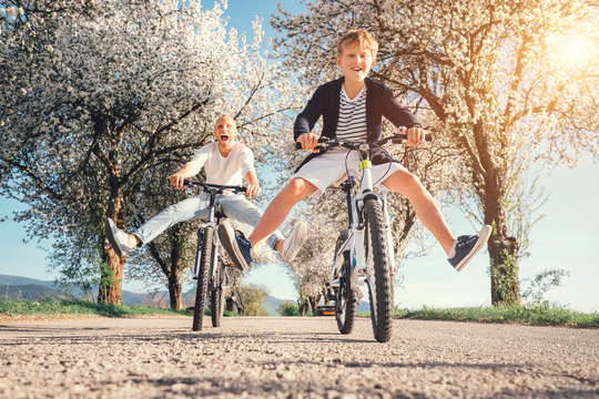 Father and son have a fun when riding bicycles on country road with blossom trees