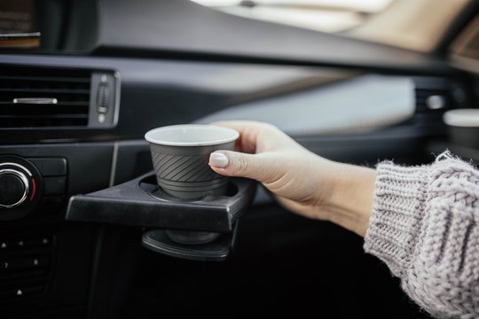cup holder in the car. female hand with coffee on a trip.