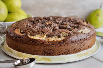 Homemade Chocolate Pear Cake.  Whole cake close up.  Ripened pears in the background.