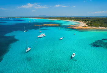 Fototapeta na wymiar Aerial view of boats and luxury yachts in the clear sea at sunset in summer in Mallorca, Spain. Colorful seascape with lagoon, azure water, sandy beach, blue sky. Balearic islands. Top view. Travel