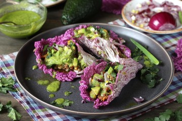 taco keto diet food is wrapped instead of cakes in cabbage leaf of Peking cabbage with avocado mayo, diced avocado, ground beef, onions, corn and cilantro, healthy fats without carbohydrates.