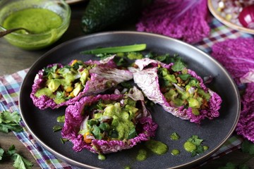 taco keto diet food is wrapped instead of cakes in cabbage leaf of Peking cabbage with avocado mayo, diced avocado, ground beef, onions, corn and cilantro, healthy fats without carbohydrates.