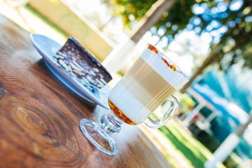 Latte coffee and cake on wooden table at outdoor