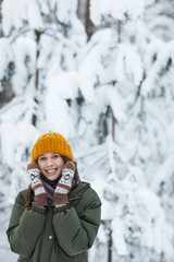 Fototapeta na wymiar Waist up portrait of happy young woman posing in beautiful winter forest against snowy pine trees, copy space