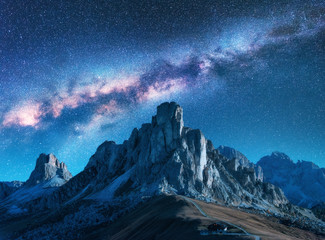 Milky Way above mountains at night in summer. Landscape with alpine mountain valley, blue sky with milky way and stars, buildings on the hill, rocks. Aerial view. Passo Giau in Dolomites, Italy. Space - Powered by Adobe