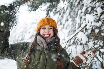 Waist up portrait of happy young woman posing outdoors in winter standing under beautiful pine trees, copy space