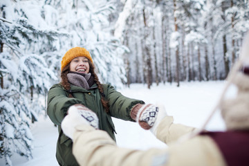 Fototapeta na wymiar Waist up portrait of playful young couple having fun outdoors in winter and holding hands, copy space