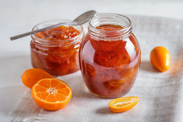 Tangerine and kumquat jam in a glass jar on white  background.