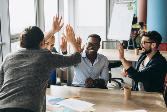 Work colleagues gathered around the table in positive mood to discuss working moments during the work process