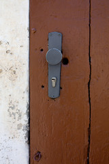 Painted grey door handle and keyhole of a brown barn door