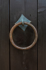 Rusty door ring knocker on an entrance wooden door
