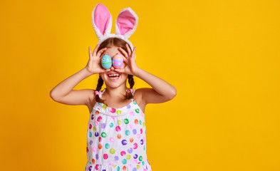funny happy child girl with easter eggs  on yellow.