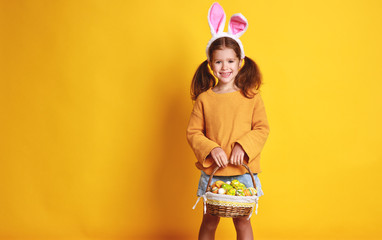 funny happy child girl with easter eggs  on yellow.