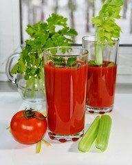 Fresh tomato juice with celery and parsley. Two glasses of refreshing drink on a kitchen table. Healthy lifestyle. Homemade beverages from vegetable. Food Photography