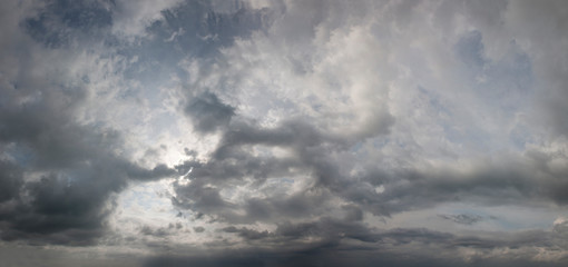 Panorama of cloudy sky. Dramatic atmosphere preceding the storm. Threatening sky with dark clouds. Sun rays through dark clouds of stormy sky