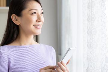 部屋でスマホを見る女性