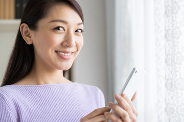 部屋でスマホを見る女性