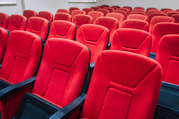 Red cineme chairs or armchairs in theater. Red chairs in conference or seminar room.
