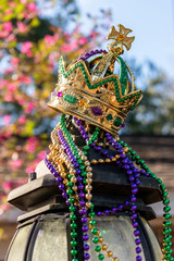 Outdoor Mardi Gras Crown and beads on light post in sunshine © Lynne Ann Mitchell