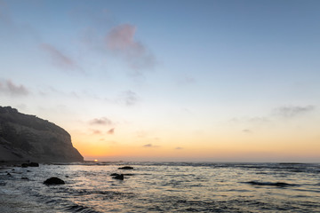Fototapeta na wymiar Amazing Las Brisas beach an awe sea coastline landscape on a wild environment in Chile. The sun goes down over the infinite horizon behind the cliffs reflected on the sea water with orange tones