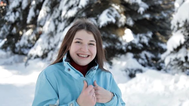 A young girl walks in the winter in the forest and poses for the camera