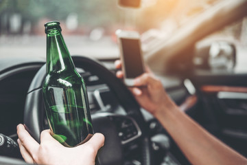 Drunk man driving a car on the road holding bottle beer Dangerous drunk driving concept