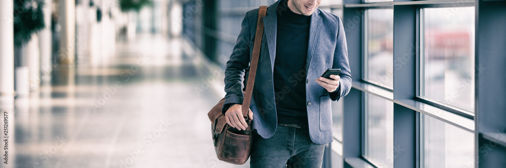 Wall mural business man texting on mobile phone commuting walking in airport with messenger bag using cellphone