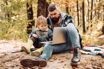 Fototapeta premium Parent teach baby. Father playing with little son in park in early autumn day. Happy joyful father with cute son in cowboy hat, family, travel, vacation, father's day - concept.