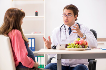 Pregnant woman visiting doctor discussing healthy diet