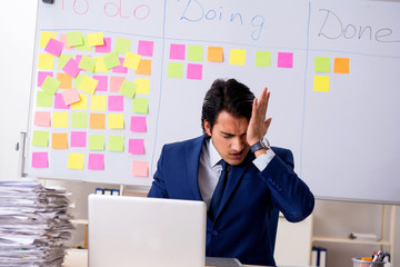 Young handsome employee in front of whiteboard with to-do list  