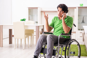 Young handsome man in wheelchair at home 