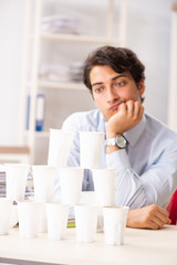 Young employee building pyramid from plastic cups 
