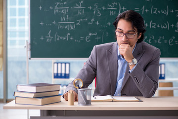 Young handsome math teacher in classroom 
